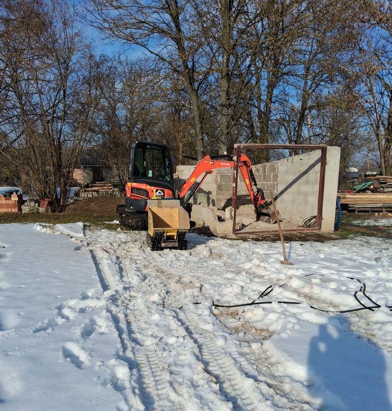 Minibagger und Dumper beim kontrollierten Rückbau einer gemauerten Wand im Winter