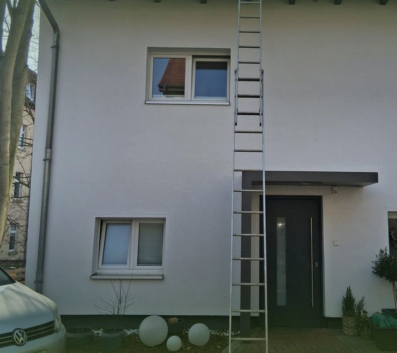 Leiter an der Fassade eines Einfamilienhauses während der Dachpflege