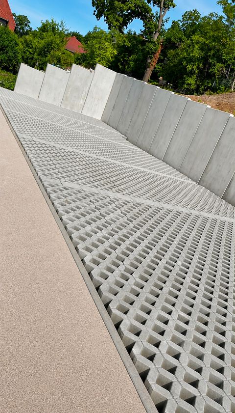 Neu verlegte Rasengittersteine entlang einer Beton-Stützwand