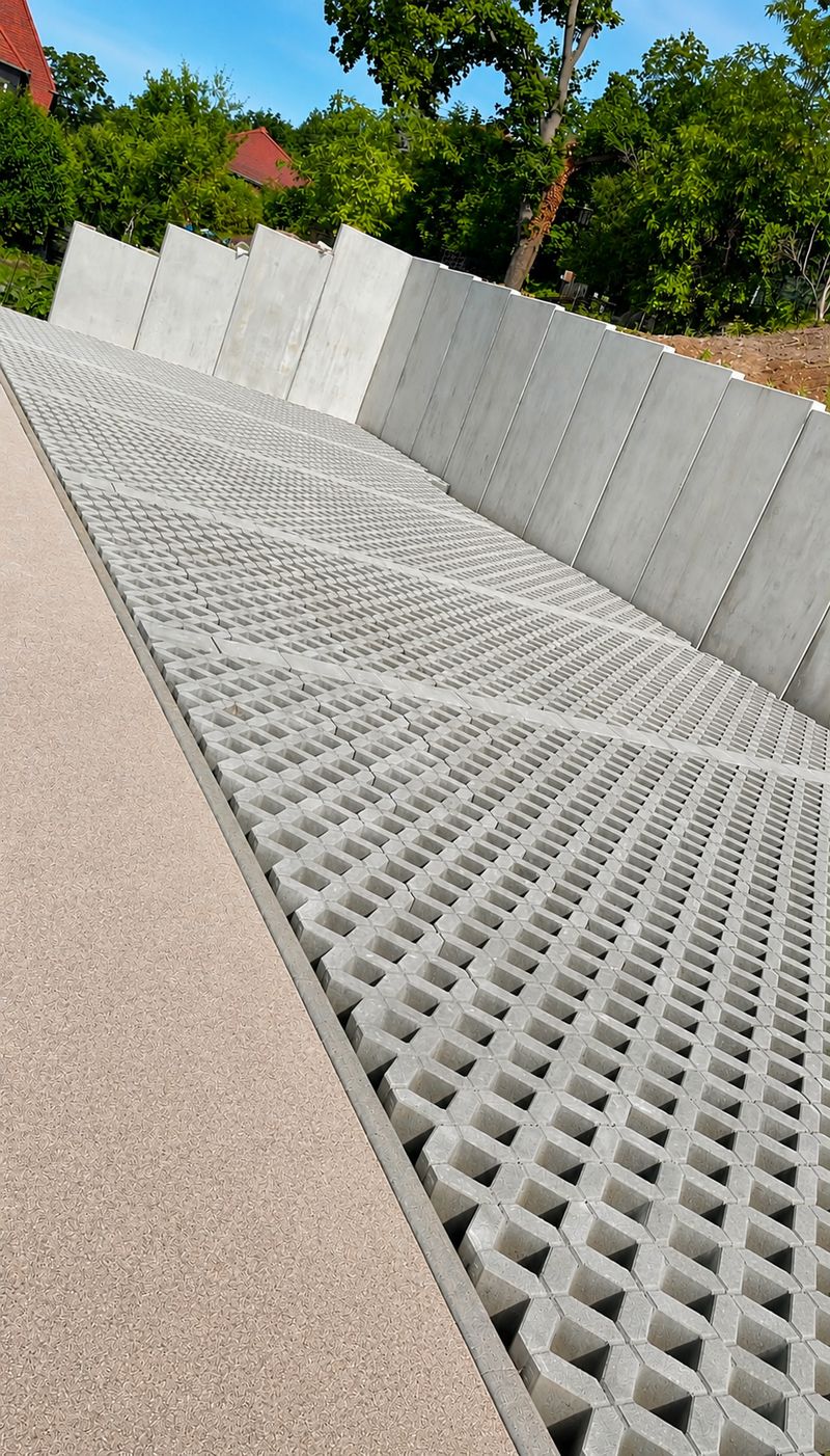 Neu verlegte Rasengittersteine entlang einer Beton-Stützwand auf einem Grundstück