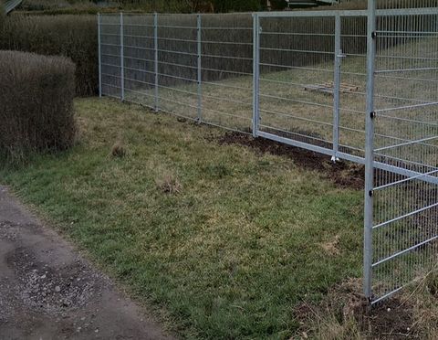 Fertig montierte verzinkte Zaunanlage mit Tor entlang einer Grundstücksgrenze