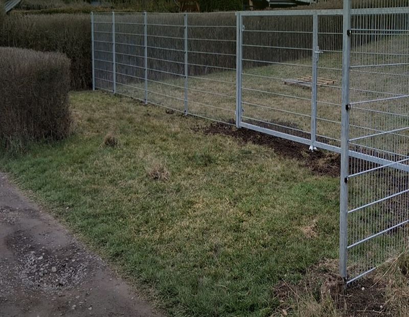 Fertig montierte verzinkte Zaunanlage mit Tor entlang einer Grundstücksgrenze